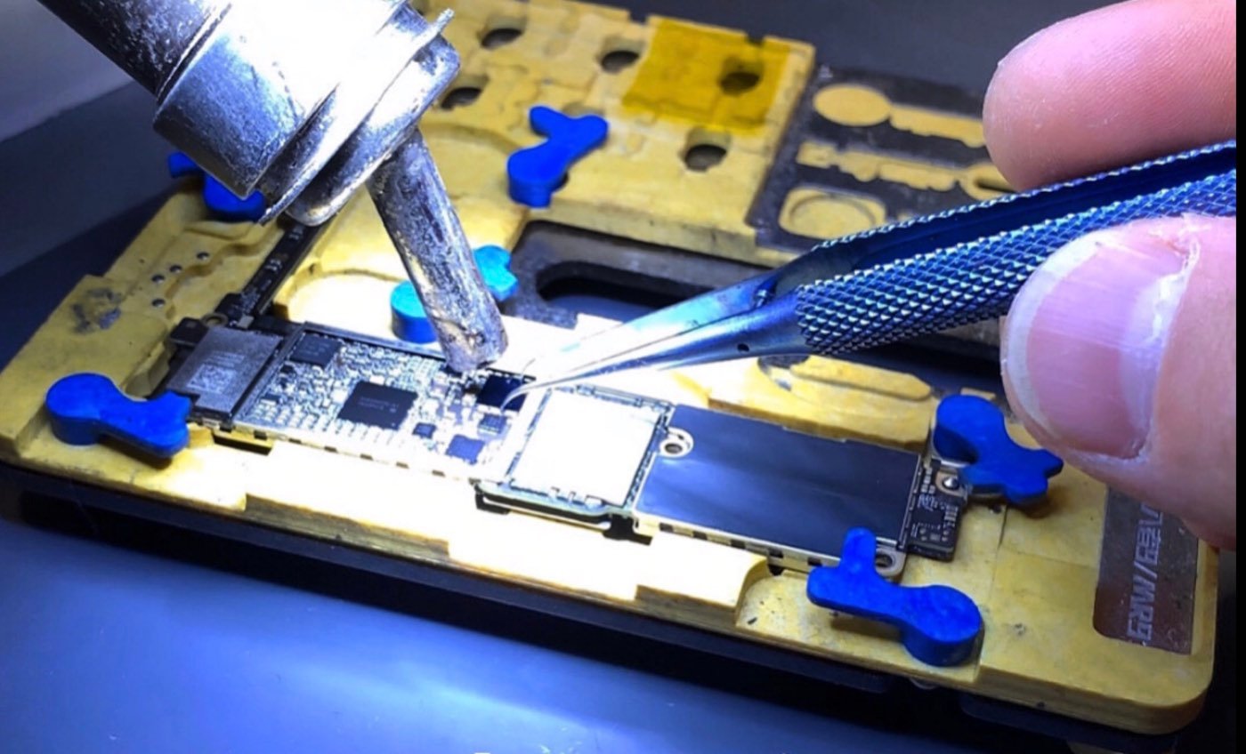 Microsoudure sur une carte mère d'iPhone, à l'établi du Comptoir des Mobiles